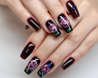 Glossy dark red and black press-on nails with abstract swirl nail art on a hand, featuring long square-shaped tips and a salon-quality high-