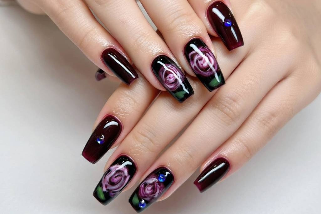 Glossy dark red and black press-on nails with abstract swirl nail art on a hand, featuring long square-shaped tips and a salon-quality high-