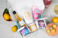 A person holds a teal Bath Bevy monthly subscription box tied with a red ribbon, ideal for self care gifts