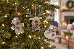 The handmade wooden gingerbread man, reindeer and snowman ornaments hanging from gingham ribbon loops on a lit Christmas tree