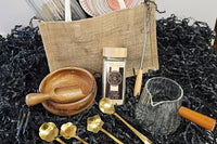 A beautifully curated set: jute bag, vanilla sugar, gold spoons, acacia bowl & scoop, glass jar, and measuring cup.