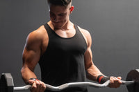 This image shows a fit male model doing bicep curls with a weighted bar while wearing Meat Sportsclub wrist wraps, a Q3 Gainz Box product.