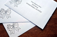 Close-up of three white envelopes with printed sample U.S. addresses and black outline patriotic bow designs on a wooden table.