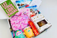 Colorful items in the TWEEN WISHBOX subscription box include gel pens, a notebook, and fun accessories for tween girls