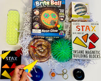 Teen Box has Brite Ball, Simple Dimple, Snake, Stax Magnetic Blocks, Land of Dough, Snapperz, Pencil Case Bubble Pop, Needoh, Puffer Bal