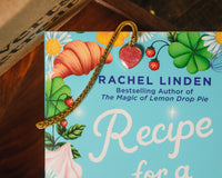 Introverts Retreat closeup of one of our books with a metal bookmark with a heart-shaped charm next to a box.