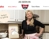 Bright lemon cupcakes topped with pink strawberry buttercream swirls and white sugar pearls in a baking kit setup