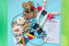 A variety of bird toys spilling out of a cardboard box and onto a blue cloth. Next to it is an itemized receipt and a business card. 