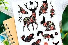 A notebook with a woodland animal sticker sheet.  Animals include a deer, owl, rabbit and more - all decorated with pink and silver foil