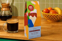Two bags of coffee, a Goodbirds box and a cup of coffee, part of Goodbirds monthly coffee subscription of 2 12oz bags of coffee