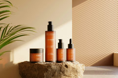 High quality photo of 4 spa and skin care products layed next to each other on a stone. With brown walls behind it.