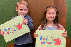 Two children holding a Wiggle Worms Kit, smiling with excitement for a new crafting adventure.......