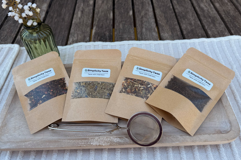 Displayed on a table with placemat, a Deluxe Monthly Subscription pack, four packs of loose leaf teas and first month reusable infuser.