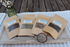 Displayed on a table with placemat, a Deluxe Monthly Subscription pack, four packs of loose leaf teas and first month reusable infuser.