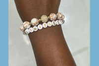 Handmade encouragement bracelet with white stone beads, clear faux crystal accents, and white letter beads spelling “LIMITLESS” 