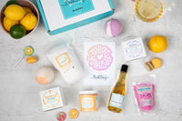 A person holds a teal Bath Bevy monthly subscription box tied with a red ribbon, ideal for self care gifts