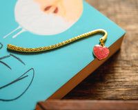 Introverts Retreat box closeup of a corner of a novel with a gold bookmark with a sparkling heart charm.