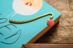 Introverts Retreat box closeup of a corner of a novel with a gold bookmark with a sparkling heart charm.