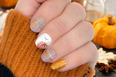 styled nail wraps displaying a pumpkin with a hand-sketched look on a plaid pattern using white, gold and green colors, and golden glitter