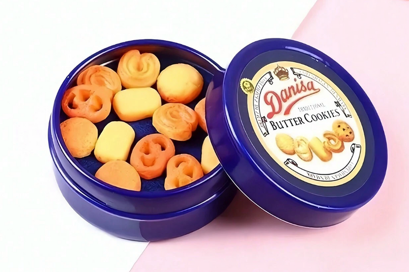 This is a photograph of a tiny blue miniature cookie tin of danish butter cookies.  The lid is off and you can see the cookies inside. 