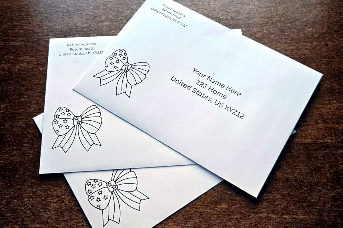 Three white envelopes with printed sample U.S. mailing addresses and black outline patriotic bow designs arranged on a wooden table.