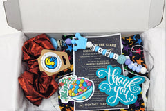 Starry night multicolored star cloth diaper subscription box with teething pacifier clip, stickers, scrunchie for mom and thank you cards.