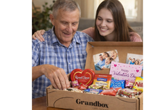 An elderly man opening a Grandbox gift box alongside a young woman, sharing an emotional moment with family photos and Valentine's Day gifts