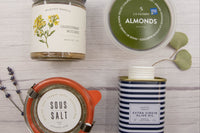 Overhead view of a McEvoy Ranch extra virgin olive oil tin with La Saison almonds, McEvoy Ranch Chardonnay mustard, and a jar of Sous Salt