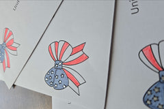 Close-up of red, white and blue patriotic bow designs with stars and stripes printed on white envelopes.
