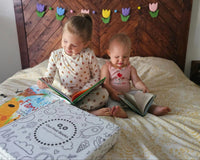Two young children reading books with an Owl Post Books kids book club subscription box, the perfect holiday gift for families.