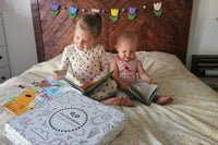 Two young children reading books with an Owl Post Books kids book club subscription box, the perfect holiday gift for families.