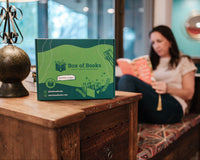 Woman relaxing in a book nook while reading a book she recently received from her book subscription.