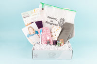 Open IndieStitch box featuring the Ivy Color-blocked Tee from Sinclair Patterns. Other objects in the box include fabric and project bag.
