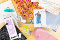 Flat lay of fabric, elastic, needles, and snips with a photo of the Donovan Skirt from Helen's Closet sewing pattern. 