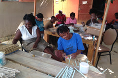Several artisans hard at work in Haiti painting clay beads. These artisans work for Papillon Marketplace. 