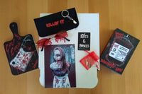 A closed Bats and Bones subscription box surrounded by a chopping board, shower gel that looks like blood and sunglasses.