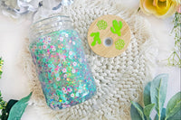 mason jar glass can snow globe cup. Inside are cactus and flower sprinkles with green glitter. Bamboo lid with holographic vinyl.