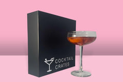 Cocktail subscription box displaying a manhattan cocktail in front of a gift box from Cocktail Crates