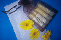 4 Natural, homemade lip balms in an organza bag, surrounded by the calendula flower they are made with. 