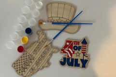 Three wooden patriotic shapes with 2 paint brushes and a paint sampler. One of the shapes is painted as an example.