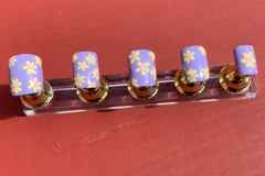 Set name: Flower Power. Pastel lilac base with yellow and pink daisy flowers. Pinky nail has a single daisy.