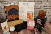 The 2023 Winter Box includes a tea glass with a blooming tea and lavender honey, a journal, a candle, a chai hand salve and an eye mask.