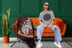 Young woman on orange couch wearing a Deathly Hallows Tshirt. A Slytherin journal and Gryffindor blanket are next to her.