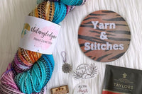 A sample of the Hand Dyed Yarn, stitch marker and extra items that will be offered in each quarterly box.