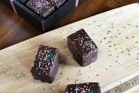 Nettie's Craft Brownies rainbow cookies sprinkles chocolate dipped wood cutting board box of brownies.