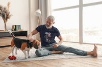 Man in his apartment with his beagle sitting on a rug taking a break from a workout. The man is wearing a Darth Vader Tshirt.