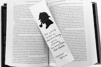 A black and white bookmark with a image of sherlock holmes and a quote sits on an open hardcover book.