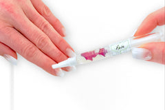Woman's hands with natural french nails applying the Rose Botanical Nail Pen to her cuticle and nail beds.