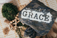 our rugged and resilient camo print tee, adorned with a bold design proudly proclaiming "Saved by Grace."