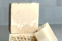 cream and white swirled bars of soap stacked on top of each other with a bar leaning on the stack. This is the Triple Butter Honey soap. 
